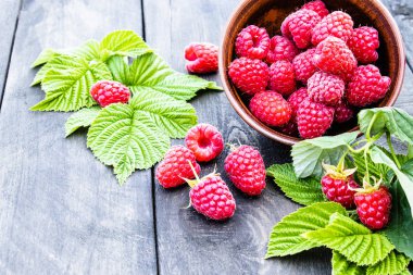 Eski koyu tahtaların arka planında yaprakları ile Taze ahududu. Seçici odaklama.