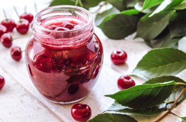 Meyveler ve yeşil yaprakları yakın ahşap bir arka planda meyve ile taze kiraz jöle.