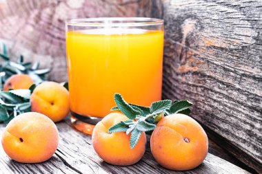 Eski tahtaları arka planda kayısı ve yeşil nane dalları ile taze kayısı suyu.