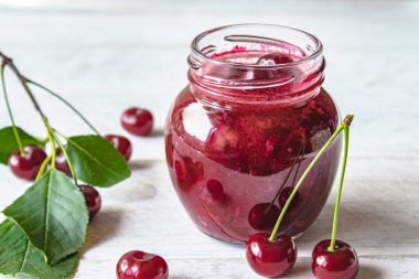 Meyveler ve yeşil yaprakları yakın ahşap bir arka planda meyve ile taze kiraz jöle.