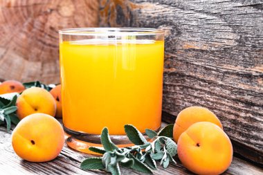 Eski tahtaları arka planda kayısı ve yeşil nane dalları ile taze kayısı suyu.