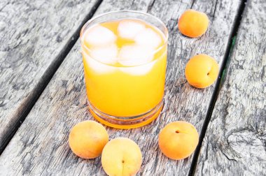 Eski tahtaları arka planda bir bardak kayısı ve buz küpleri ile taze kayısı suyu. Yaz alkolsüz içecekler.