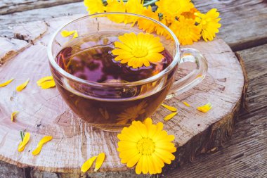 Şeffaf cam kupa Calendula çiçekler bitkisel çay. Bardağın Calendula tentürü özü.