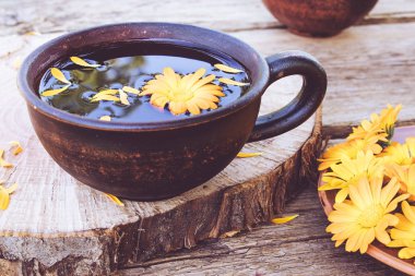 Bir kupa içinde Calendula çiçekler bitkisel çay. Bardağın Calendula tentürü özü.