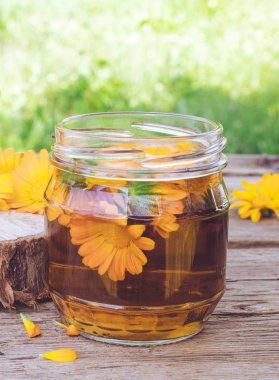 Bir cam taze çiçekler ile Calendula tincture ekstresi doğada ahşap bir arka plan üzerinde olabilir. Calendula tentürü özü.