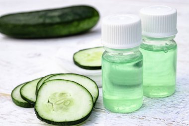 Dilimlenmiş salatalık ve bir şişe salatalık özü. Cilt bakımı için sıvı kozmetik.