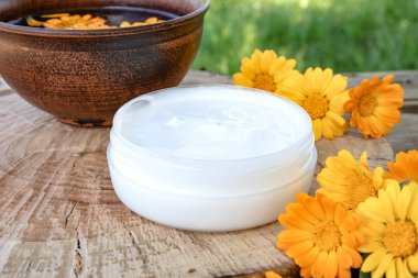 Doğada ahşap bir arka planda taze Calendula çiçekler ile Calendula özü ile besleyici krem.