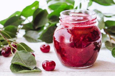 Meyveler ve yeşil yaprakları yakın ahşap bir arka planda meyve ile taze kiraz jöle.