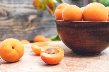 Kayısı yakın ahşap bir masada bir kase olgun sarı kayısı.