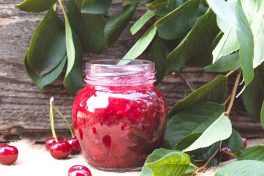 Meyveler ve yeşil yaprakları yakın ahşap bir arka planda meyve ile taze kiraz jöle.