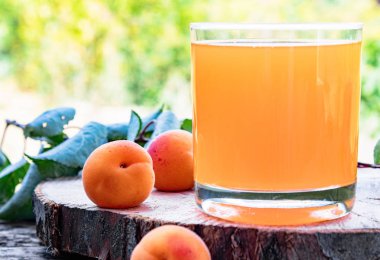 Doğanın arka planına karşı bir masada taze kayısı suyu ve kayısı.