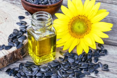 Ayçiçeği ve tohumlar cam bir kavanozda ayçiçek yağı yakınında ahşap bir arka plan üzerinde. Sağlıklı gıdalar ve yağlar.
