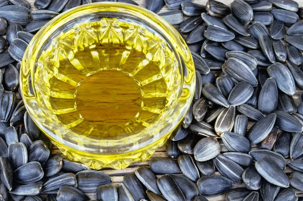 Sunflower oil and sunflower seeds on a wooden background. Healthy foods and fats.