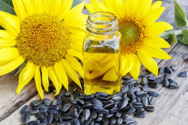 Ahşap bir arka plan üzerinde tohum ve taze çiçekler ile cam bir kavanozda Organik ayçiçek yağı. Sağlıklı gıdalar ve yağlar.
