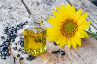 Ahşap bir arka plan üzerinde tohum ve taze çiçekler ile cam bir kavanozda Organik ayçiçek yağı. Sağlıklı gıdalar ve yağlar.