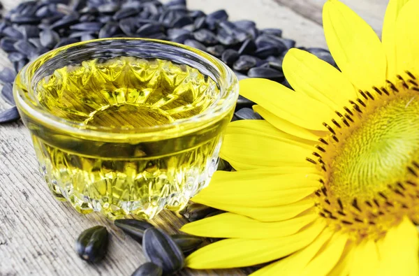 Sunflower oil with seeds on a wooden background near fresh sunflower flowers. Organic and eco food. — Stock Photo, Image