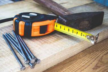 Çivili eski çekiç ve tahta zeminde rulet in sarı bir cetvel. İnşaat işleri için araçlar.