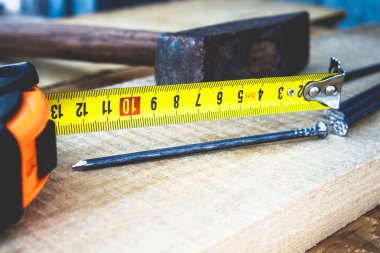 Çivili eski çekiç ve tahta zeminde rulet in sarı bir cetvel. İnşaat işleri için araçlar.