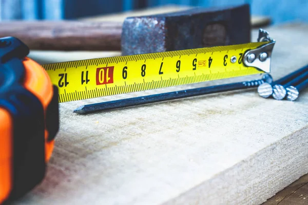 Çivili eski çekiç ve tahta zeminde rulet in sarı bir cetvel. İnşaat işleri için araçlar.