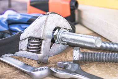 Ayarlanabilir bir spanner ahşap panoların arka planına karşı yıkıtan cıvata ve somun yakınında yatıyor.