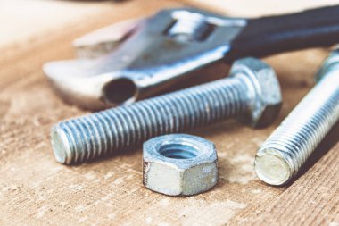Ayarlanabilir bir spanner ahşap panoların arka planına karşı yıkıtan cıvata ve somun yakınında yatıyor.