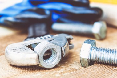 Ayarlanabilir bir spanner ahşap panoların arka planına karşı yıkıtan cıvata ve somun yakınında yatıyor.