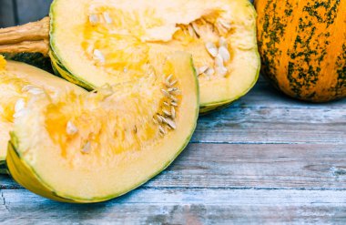 Olgun turuncu kabak mavi eski tahtalarda tohumları ile dilimlenmiş.