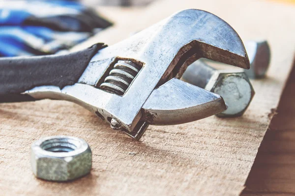 Ayarlanabilir bir spanner ahşap panoların arka planına karşı yıkıtan cıvata ve somun yakınında yatıyor.