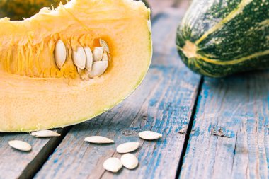 Olgun turuncu kabak mavi eski tahtalarda tohumları ile dilimlenmiş.