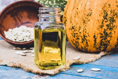 Kabak çekirdeği esansiyel yağı bir şişe yakın çekim çuval ile bir peçete üzerinde.