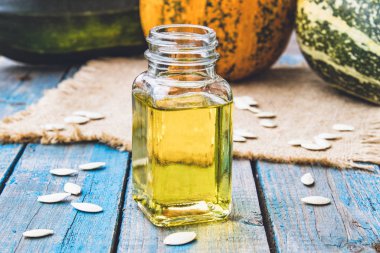 Kabak çekirdeği ve uçucu yağ mavi eski panoları kabak yakın bir şişede.