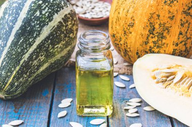 Mavi eski tahtalarda bir kabak yakın bir şişede kabak çekirdeği uçucu yağ.