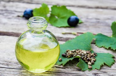 Bir cam şişe üzüm uçucu yağ ve eski ahşap tahtalar üzerinde zar. Mavi üzüm. Spa, eko ürünler konsepti.