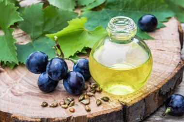 Bir cam şişe üzüm uçucu yağ ve eski ahşap tahtalar üzerinde zar. Mavi üzüm. Spa, eko ürünler konsepti.