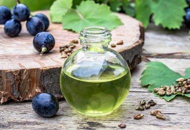 Mavi üzüm ve yeşil yapraklarıgrones yakın eski ahşap tahtalarda üzüm çekirdeği esansiyel yağı ile Şişe. Spa, eko ürünler konsepti.