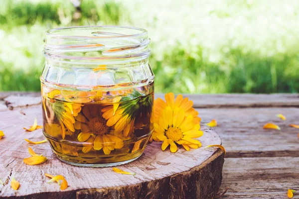Bir cam taze çiçekler ile Calendula tincture ekstresi doğada ahşap bir arka plan üzerinde olabilir. Calendula tentürü özü.