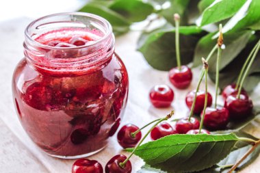 Meyve ve yaprakları yakın ahşap bir arka planda ev yapımı kiraz reçel ile banka.