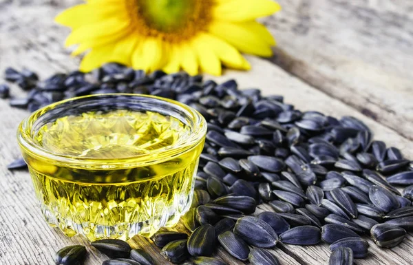 Aceite de girasol con semillas sobre un fondo de madera cerca de flores frescas de girasol. Alimentos ecológicos y ecológicos . — Foto de Stock