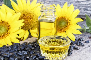 Taze ayçiçeği çiçekleri yakınında ahşap bir arka plan üzerinde tohumları ile ayçiçek yağı. Organik ve eko gıda.