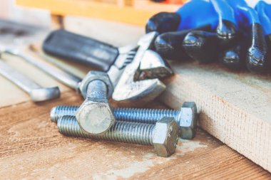 Ayarlanabilir bir spanner ahşap panoların arka planına karşı yıkıtan cıvata ve somun yakınında yatıyor.