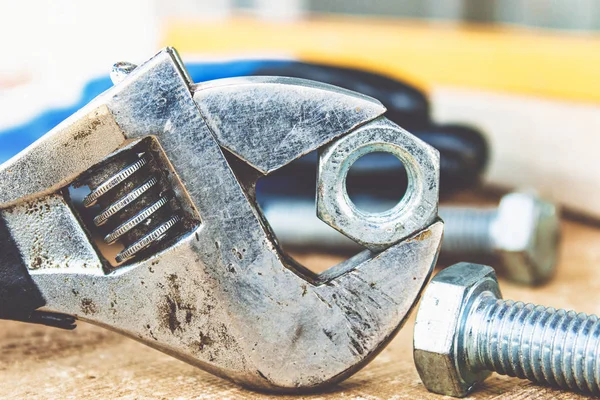 Ayarlanabilir bir spanner ahşap panoların arka planına karşı yıkıtan cıvata ve somun yakınında yatıyor.