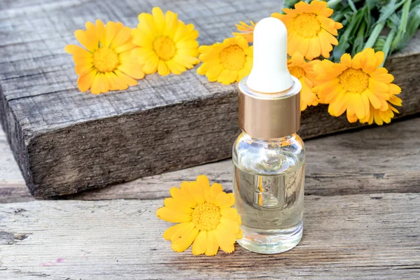 Flasche Calendula-Öl auf einem hölzernen Hintergrund. Auszug aus der Tinktur der Ringelblume. — Stockfoto