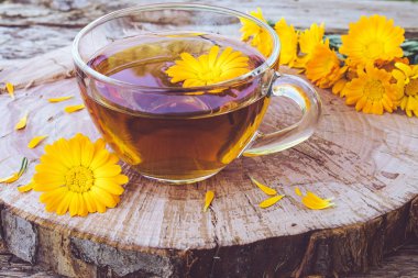 Şeffaf cam kupa Calendula çiçekler bitkisel çay. Bardağın Calendula tentürü özü.