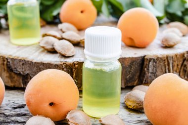 Ahşap bir masada olgun sarı kayısı yakın küçük bir kavanoz kayısı yağı.