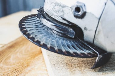 Elektrikli kesme ve öğütme makinesi. Ahşap tahtalarda aşındırıcı diskli açı öğütücü.