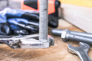 Ayarlanabilir bir spanner ahşap panoların arka planına karşı yıkıtan cıvata ve somun yakınında yatıyor.