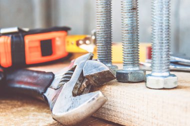 Ayarlanabilir bir spanner ahşap panoların arka planına karşı yıkıtan cıvata ve somun yakınında yatıyor.