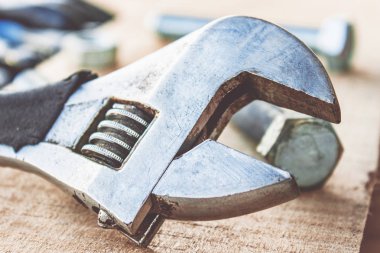 Ayarlanabilir bir spanner ahşap panoların arka planına karşı yıkıtan cıvata ve somun yakınında yatıyor.