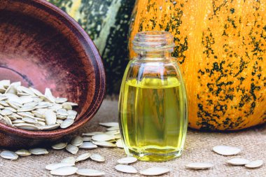 Kabak çekirdeği esansiyel yağı bir şişe yakın çekim çuval ile bir peçete üzerinde.