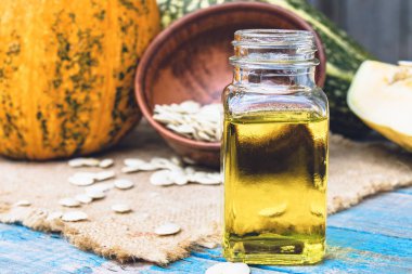 Kabak çekirdeği esansiyel yağı bir şişe yakın çekim çuval ile bir peçete üzerinde.